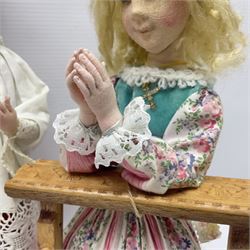 Anna Meszaros Hungary - two hand made needlework figurines, each of a young girl kneeling by an alter rail praying H28cm; together with another similar of a chorister H29cm (3)  Auctioneer's Note: Anna Meszaros came to England from her native Hungary in 1959 to marry an English businessman she met while demonstrating her art at the 1958 Brussels Exhibition. Shortly before she left for England she was awarded the title of Folk Artist Master by the Hungarian Government. Anna was a gifted painter of mainly portraits and sculptress before starting to make her figurines which are completely hand made and unique, each with a character and expression of its own. The hands, feet and face are sculptured by layering the material and pulling the features into place with needle and thread. She died in Hull in 1998.
