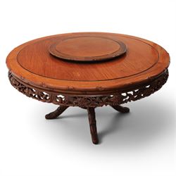 20th century Chinese ornately hardwood dining table and chairs, circular table with 'Lazy Susan' top with pierced carved frieze, raised on a quadriform base with carved foliate detail, the chairs en suite with carved pierced detailing  