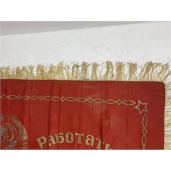 1970s Soviet banner printed in gold on a red ground, roughly translates as 'Transferable Banner - To the winner in the Socialist Competition' and 'Work Study Live by Communism' verso; wreath of wheat ears to either side; tassels on three sides 110 x 155cm