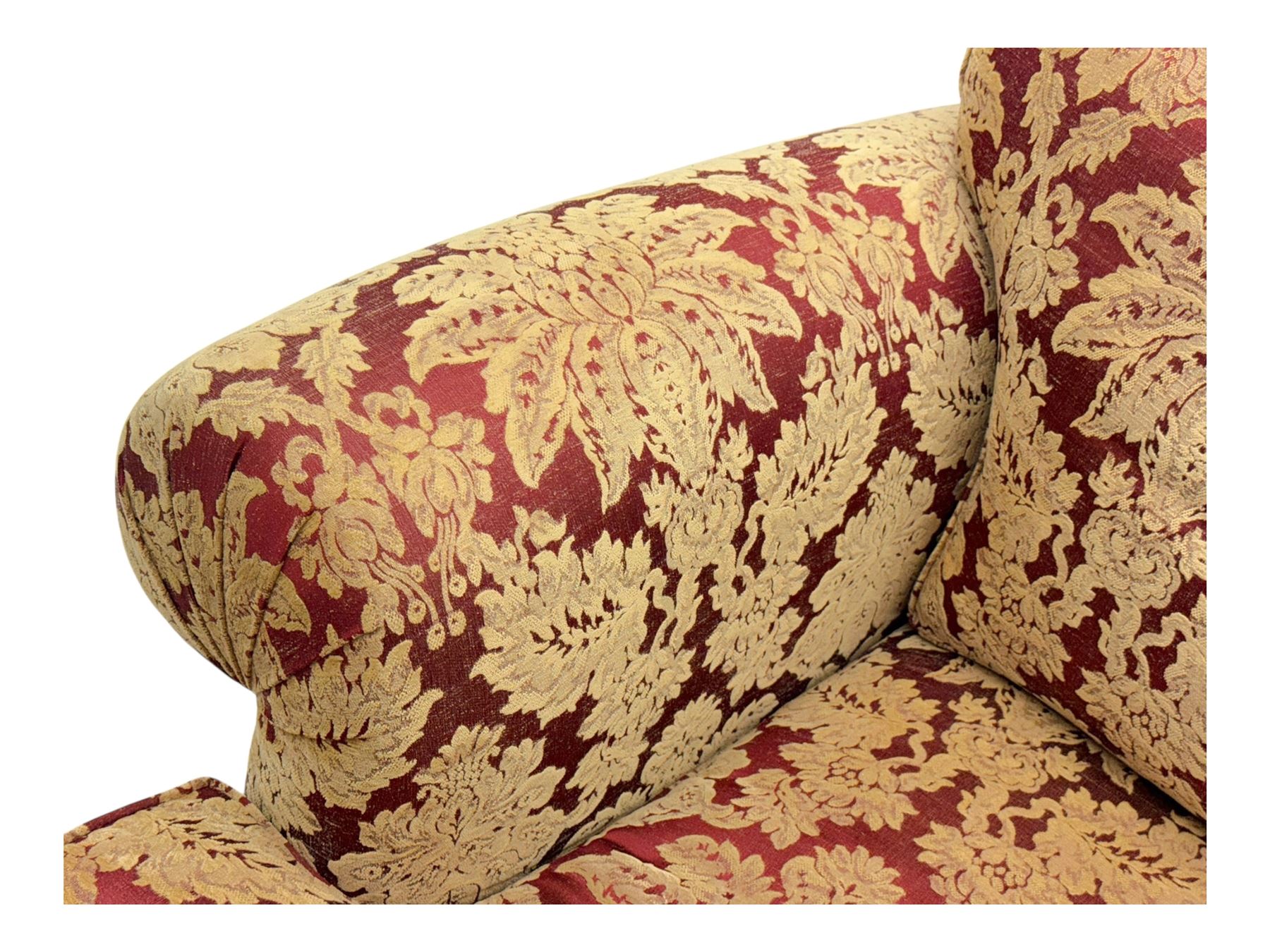 Duresta - pair of Grande three-seat sofas, traditional shaped with rolled arms and upholstered loose cushions, in red ground fabric with raised gold foliate pattern, on turned feet with brass castors 