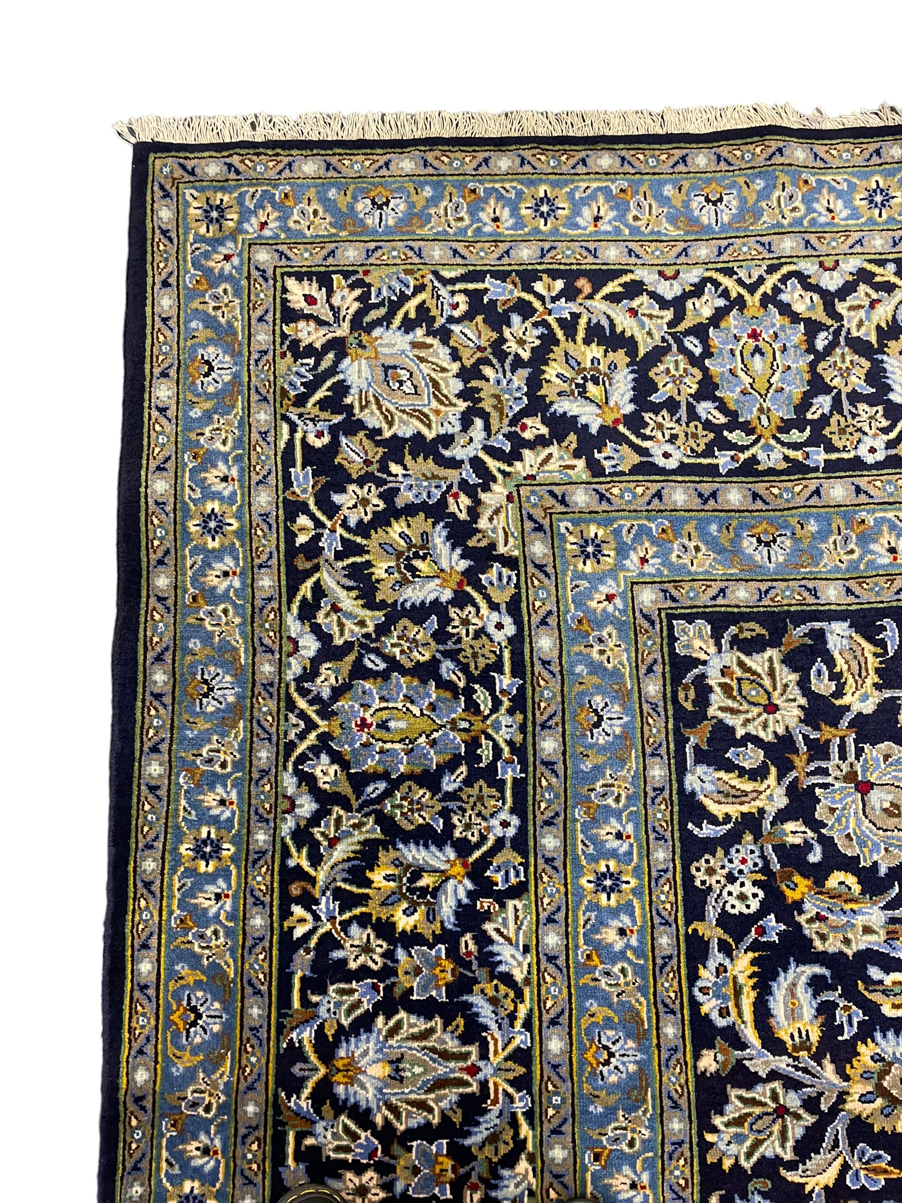 Central Persian Kashan indigo ground carpet, central lighter blue floral medallion surrounded by interlacing leafy branches and stylised plant motifs, the main border decorated with repeating floral motifs and scrolling branches, within guard stripes 