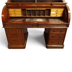 Victorian mahogany cylinder roll-top bookcase-secretaire, projecting cornice over twin glazed doors enclosing two shelves, the cylinder roll-top enclosing fitted interior with sliding drawer, hinged compartments, correspondence drawers and pigeon-holes, the twin pedestals fitted with three graduating drawers to each side, on plinth bases with castors