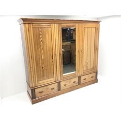 Late Victorian large pitch pine triple wardrobe, projecting cornice, central mirrored door flanked by two others above three drawers, plinth base