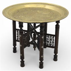 20th century Eastern brass charger topped table, the circular brass trap chased with an elephant, palm tress and flowering vines, supported upon a folding stand with six turned legs with inlaid detail, united by turned supports