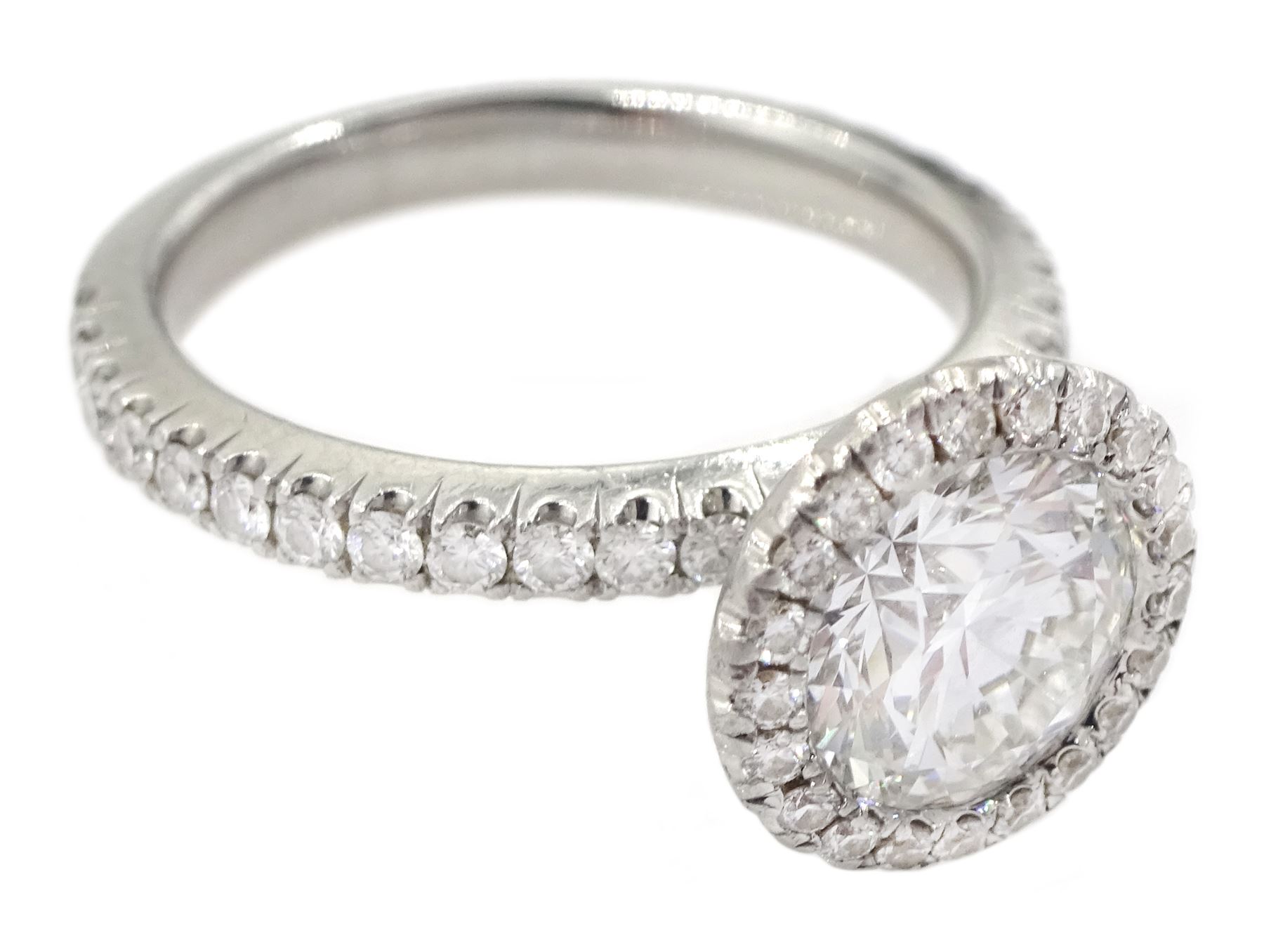 De Beers Aura platinum round brilliant diamond ring, the central diamond solitaire of 1.07 carat, clarity VVS2, colour E, with GIA certificate, surrounded by halo of diamonds and diamond set shoulders, total diamond weight 1.46 carat boxed with authenticity card and purchase receipt dated 2017