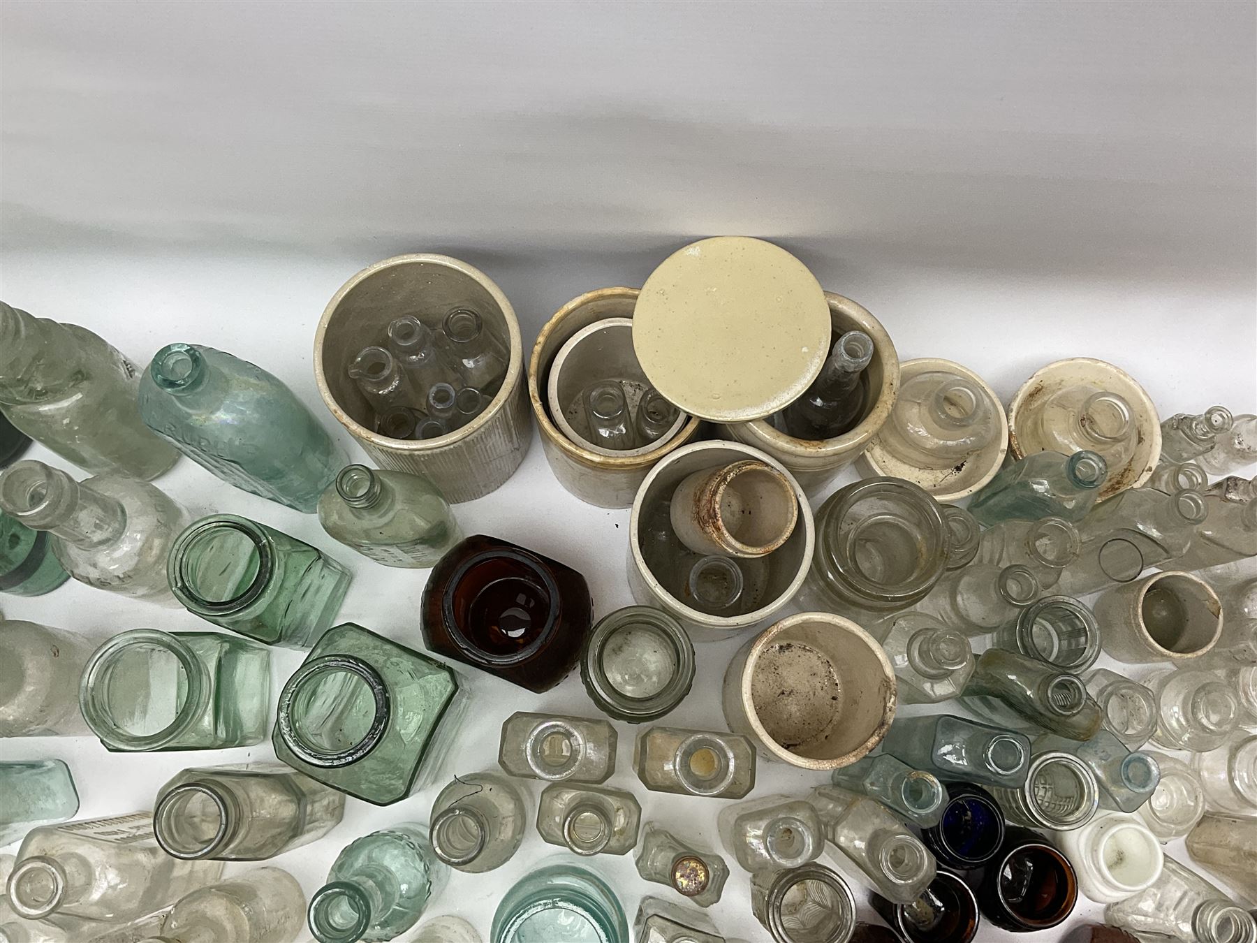 A collection of assorted glass bottles, of various size and form, mostly clear and green glass examples, plus a small group of Stoneware jars. 
