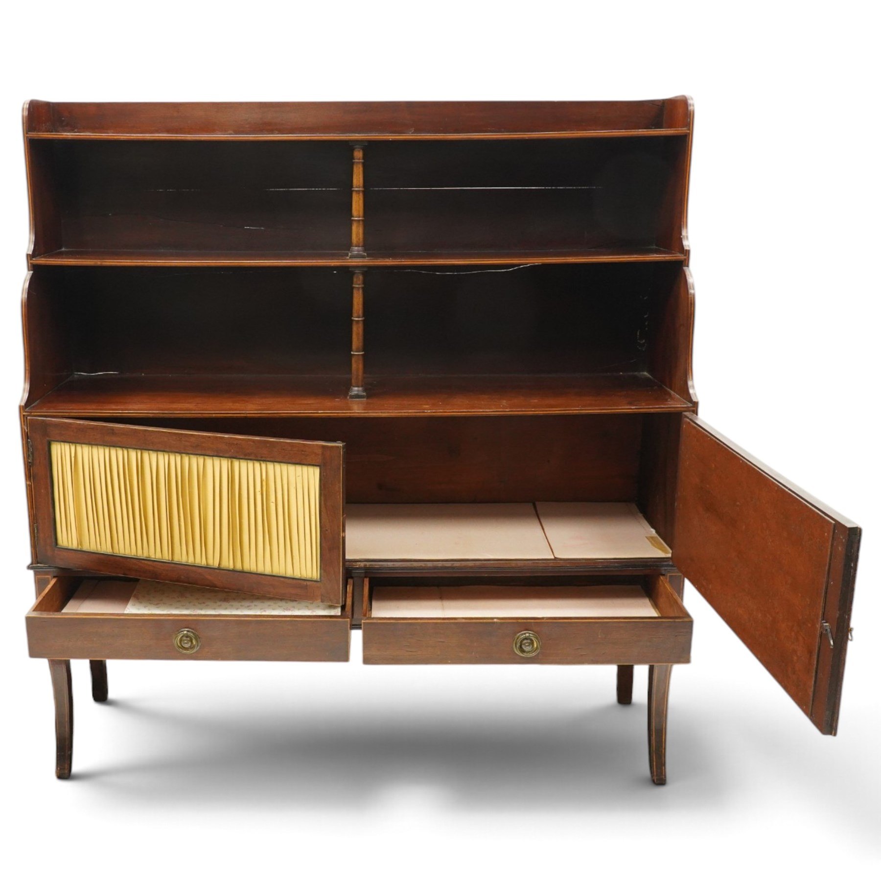 Regency period mahogany waterfall-bookcase chiffonier, the raised back with two open shelves supported by central ring-turned pilasters, fitted with twin doors with sage-green pleated fabric facias, over two drawers with satinwood stringing, raised on front sabre supports
