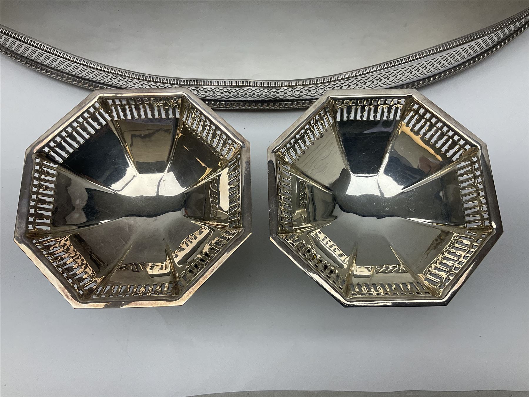 Pair of Mappin and Webb silver plate pierced pedestal bon bon dishes, together with other silver plate comprising teapot stand engraved with lion's head to centre, two cut glass claret jugs, two bottle coasters with acorn decoration, two open salts upon dolphin mounts, tea caddy, three piece cruet set and a large oval tray with pierced sides and upon four ball feet