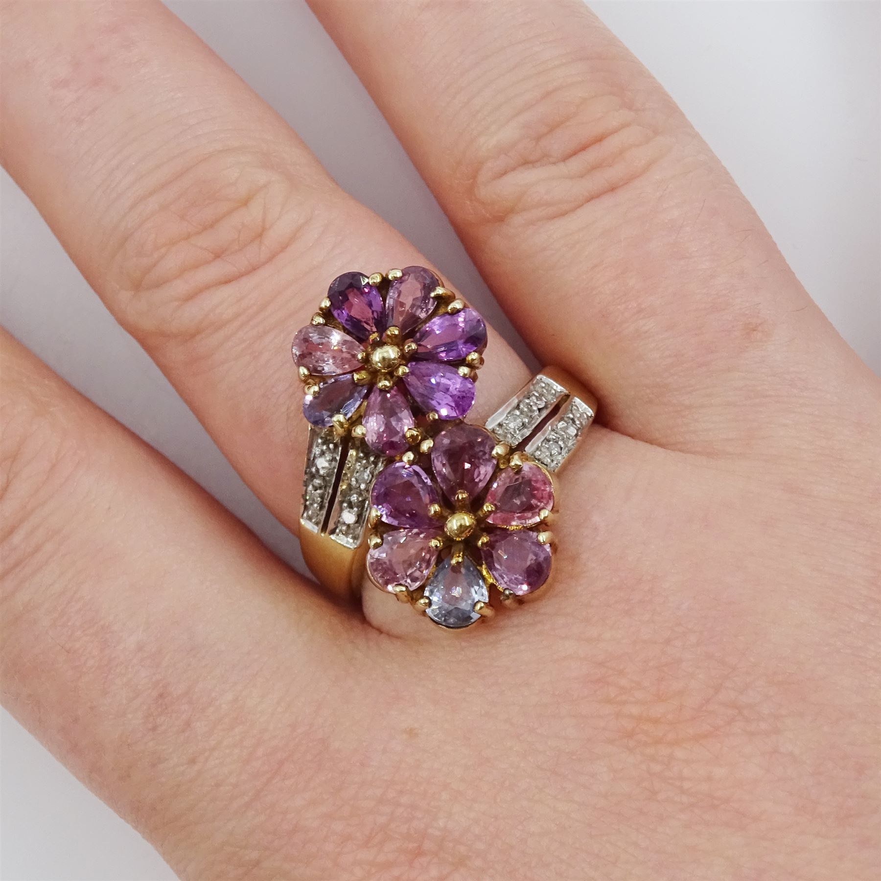 9ct gold sapphire and diamond flower head crossover ring, two flowers each set with pear cut, multi-coloured sapphires, to split diamond set shoulders, Birmingham 2006, total sapphire weight approx 3.30 carat