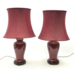A pair of burgundy ceramic lamps, of baluster form, with matching burgundy shades, overall H71cm. 