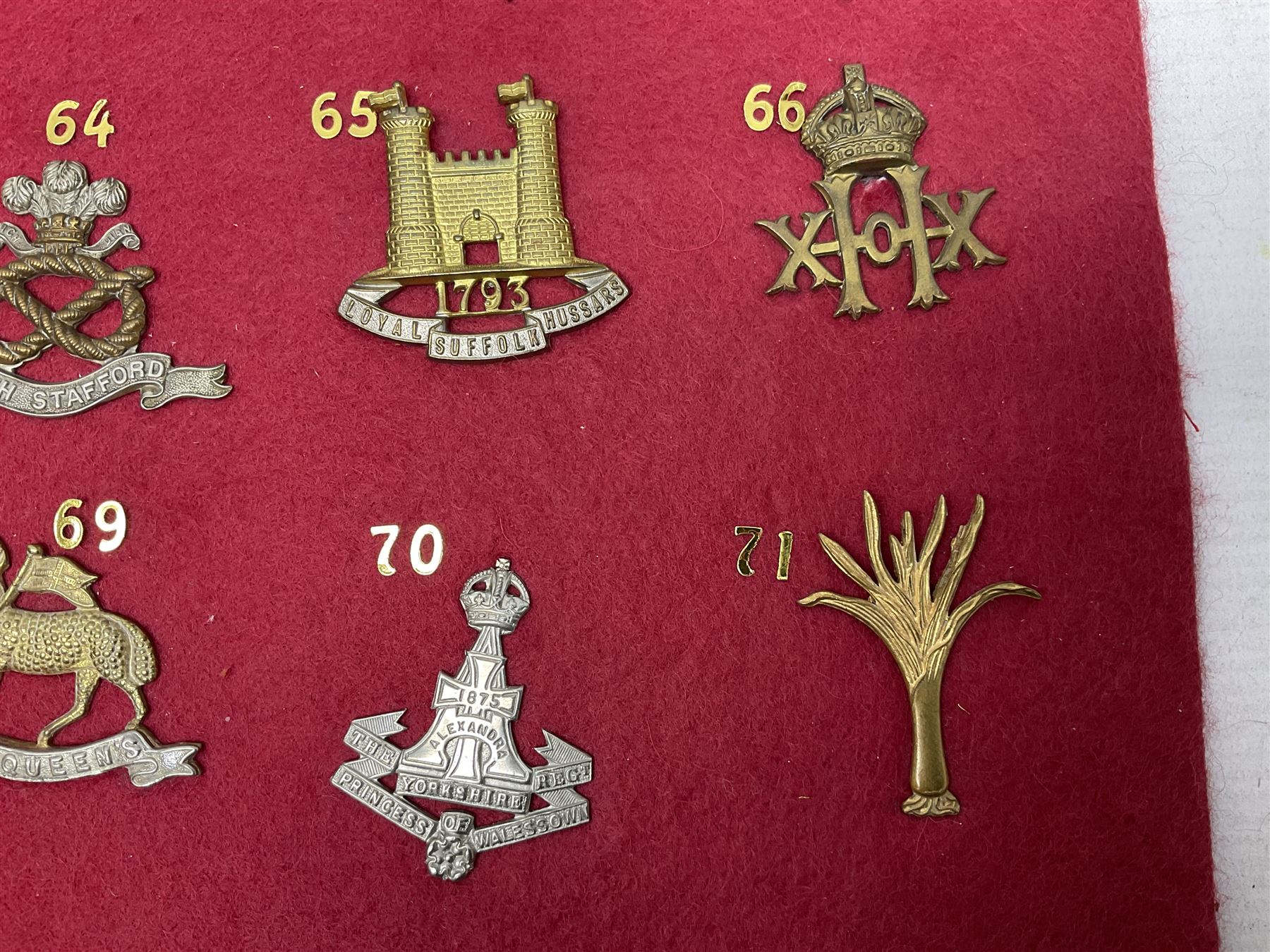 Twenty cap badges including Welsh Guards, Kings Royal Irish Hussars, York & Lancaster,  Loyal Suffolk Hussars, North Stafford, Durham Light Infantry, Cheshire, West Yorkshire, Norfolk, South Wales Borderers, Dorsetshire etc; mounted on a board for display