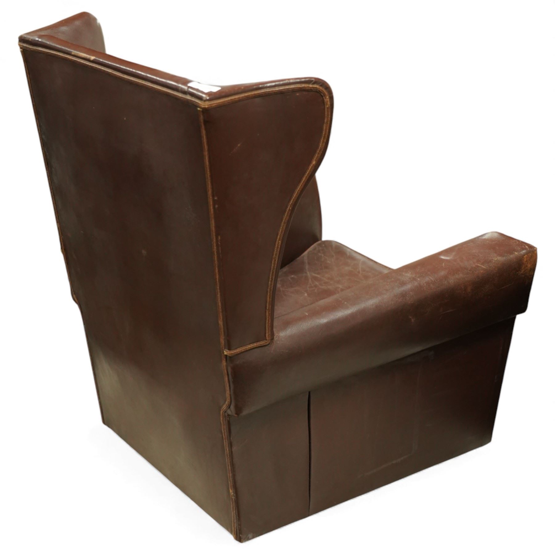Early to mid 20th century pair of wingback armchairs, upholstered throughout in chocolate brown leather, the backs with deep wings, square padded arms with piped seams, loose seat cushions over solid bases