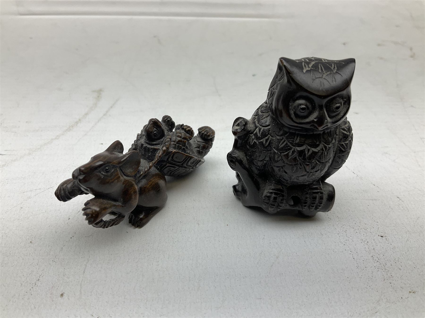 Group of ten Japanese netsukes, comprising eight carved wooden examples, and two ivorine examples, of various form, examples modelled as pigs, owl, mouse with tortoise upon its back, birds, rabbit, etc. 