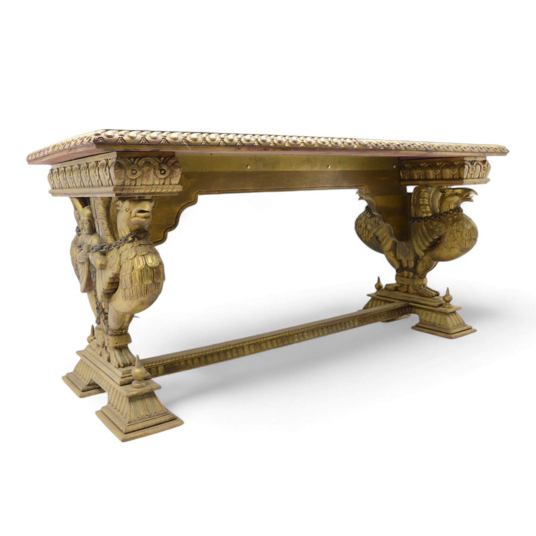 19th century Renaissance Revival carved and giltwood centre table, the rectangular top with gadrooned edge and carved frieze of repeating arched motifs with stylised scrolls, supported by a pair of carved winged griffin supports restrained by a central chained figure, on stepped rectangular bases united by carved stretcher