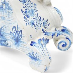 19th century delft blue and white Rococo style 8-day mantle clock, with a scrolling case and floral decoration, depiction of a courting couple in 18th century dress to the front and a contrasting scene of sailing ships on a lake to the rear, with a late 19th-century French twin train movement, enamel dial with Roman numerals, five minute Arabic's and gilt Louis XVI hands within a glazed cast bezel, with a rack striking movement sounding the hours and half-hours on a bell. No pendulum or key.  