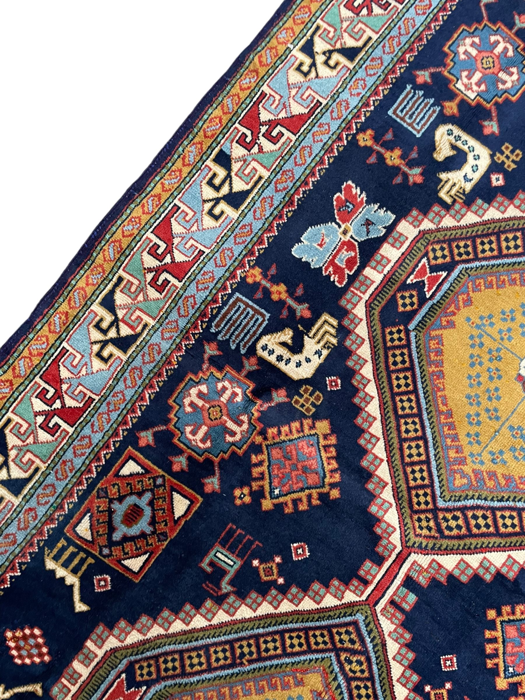 Persian Ardabil indigo ground rug, four interconnected lozenge medallions surrounded by ewer, bird, dragon, camel and geometric motifs, hooked border within guard stripes 