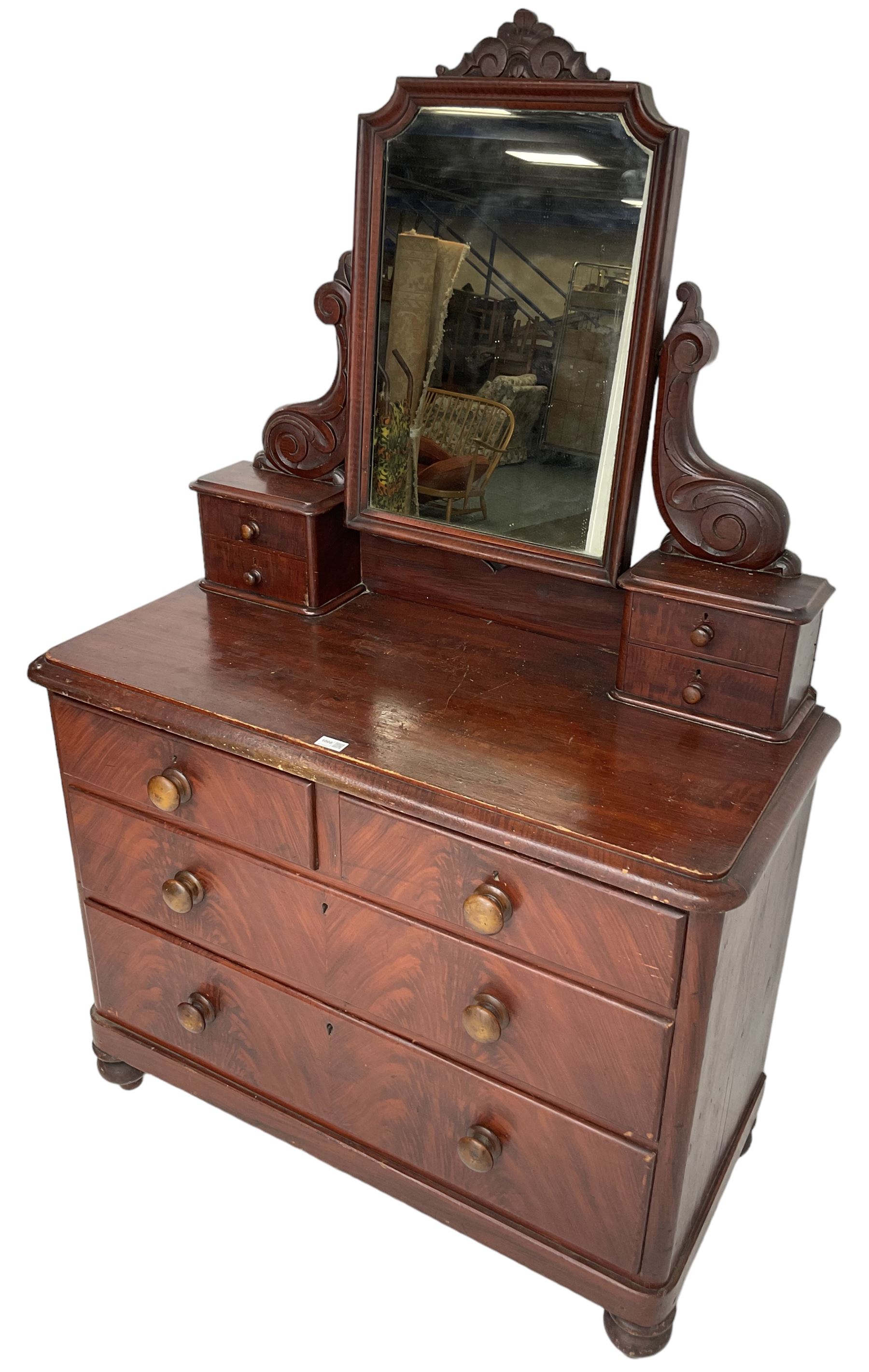 Victorian scumbled pine dressing chest, raised swing mirror in moulded frame with scrolled carved pediment, foliage S-scroll carved supports over trinket drawers, moulded rectangular top with rounded corners over two short and two long drawers, skirted base on turned feet, scumbled to resemble mahogany 