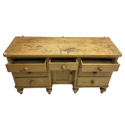 Late 19th century pine sideboard or dresser base, central drawer over recessed cupboard, flanked by six graduating drawers, raised on turned feet