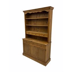 Pine dresser, three heights plate rack with drawers over sideboard fitted with drawers and cupboard, skirted base