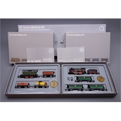  Marklin HO gauge - 1985 50th anniversary commemorative pack containing two individually boxed sets - 0-4-0 tank locomotive 'Marklin' No.00-50D freight set with three items of rolling stock and 0-4-0 electric locomotive with pantographs and three passenger coaches, each with commemorative medallion and certificate, boxed  