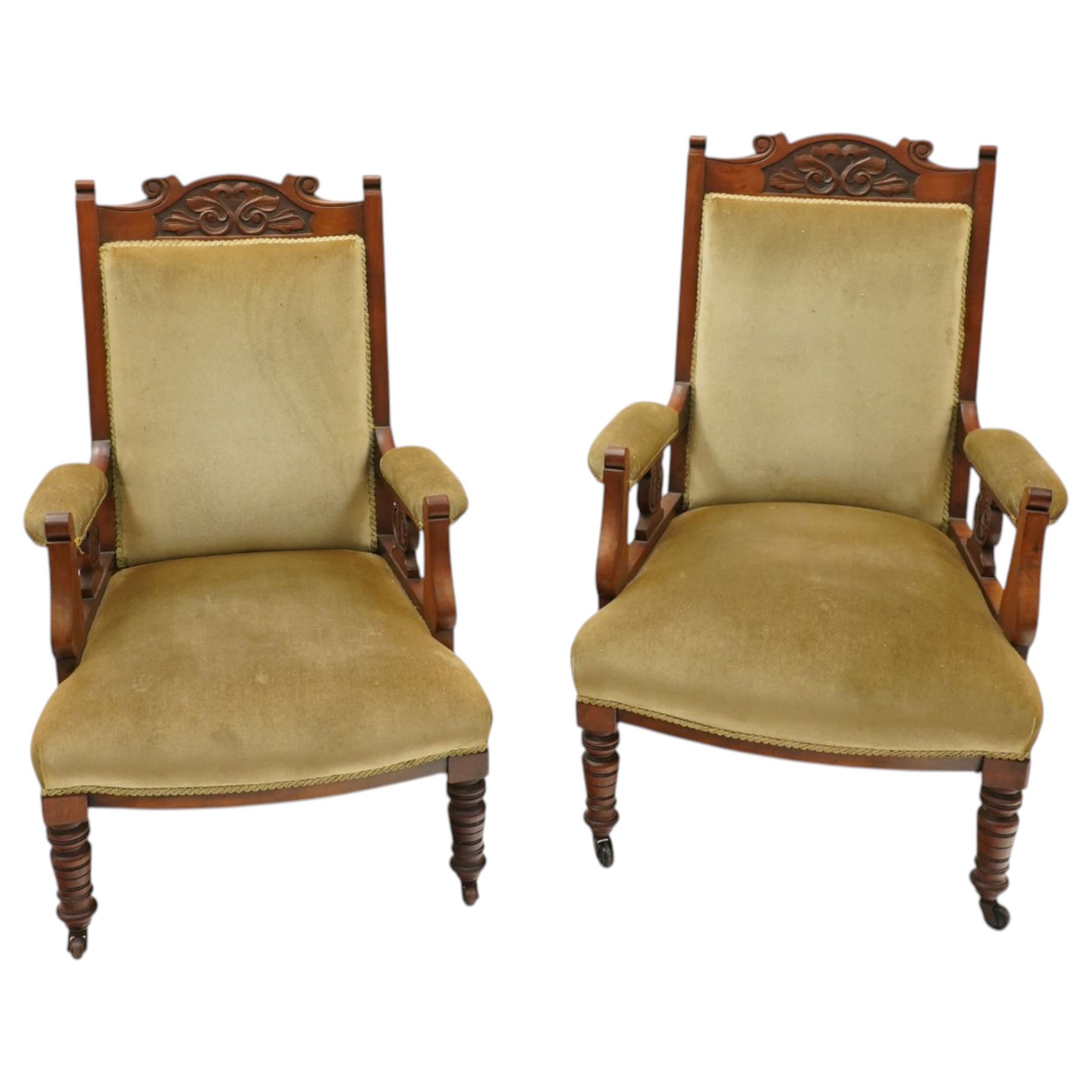 Pair of late Victorian mahogany carved open armchairs, with carved cresting rail, above upholstered seat, back and arms, raised on turned supports terminating in castors