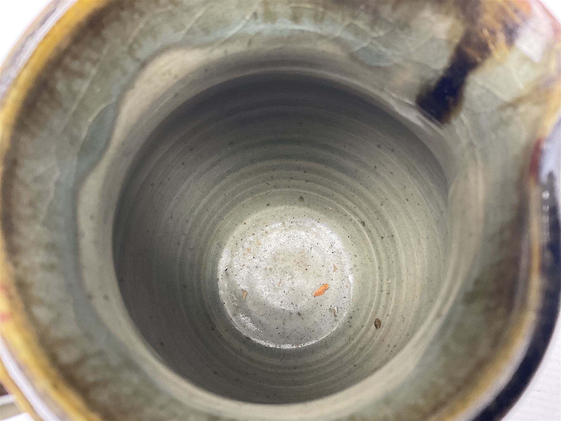 Michael Leach (British 1913-1985) for Yelland pottery; two large glazed stoneware plates with dark brown stylised decoration upon oatmeal ground, together with a jug in merging blue, green and brown, all with impressed marks beneath, largest plate D37cm