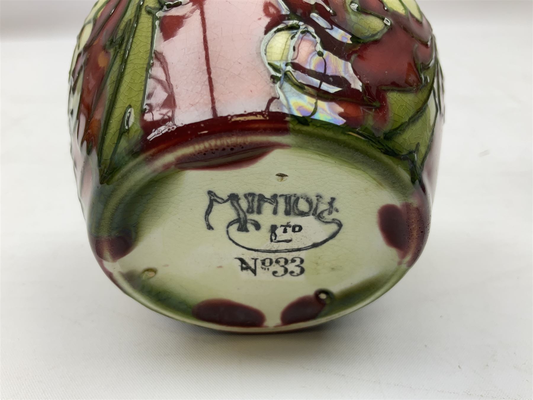 Three Minton Secessionist vases, with tube-lined stylised flower decoration, two upon a red ground and third upon a purple ground, all with printed mark to base 'Minton Ltd, No. 33', H13cm