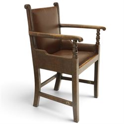 DD CL - Early 20th century oak open armchair, rectangular back with scrolled uprights, brown upholstered back and seat with brass stud edging, shaped open arms on turned supports, square legs united by stretchers