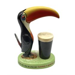 Carltonware Guinness advertising table lamp (lacking fitting) in the form of a toucan with a glass of Guinness, the base depicting 'How grand to be a toucan Just think what Toucan can do If he can say as you can Guinness is good for you', with black printed marks to the base (tail a/f)