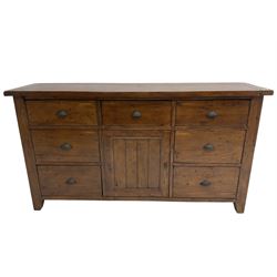 Stained pine rustic sideboard, rectangular top over seven drawers and single panelled cupboard, fitted with shell handles