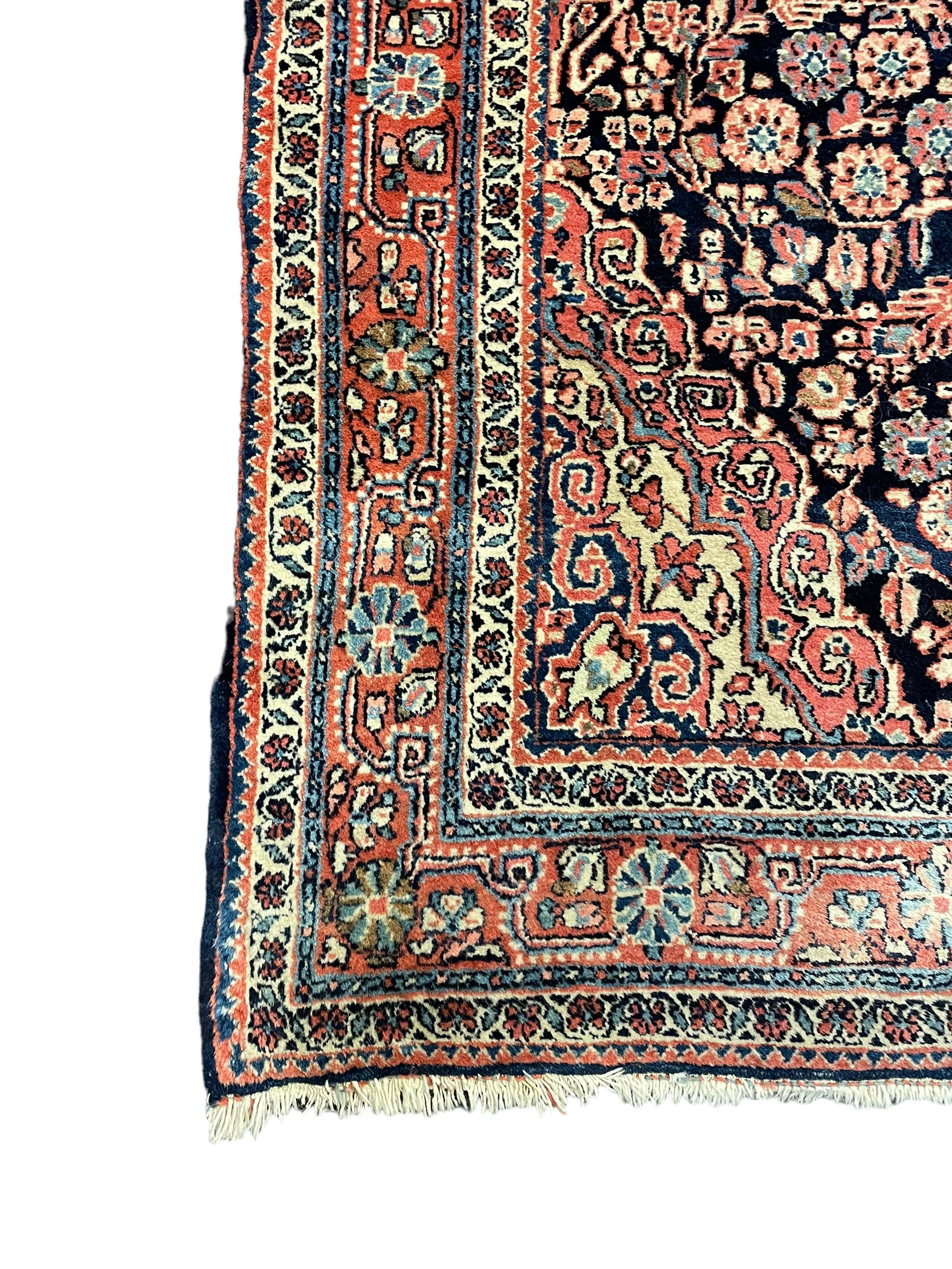 Persian indigo ground rug, the field decorated with intricate interlaced foliage branches and small flower heads, shaped floral design central medallion, the border decorated with scrolling branch and flower heads within guard bands 
