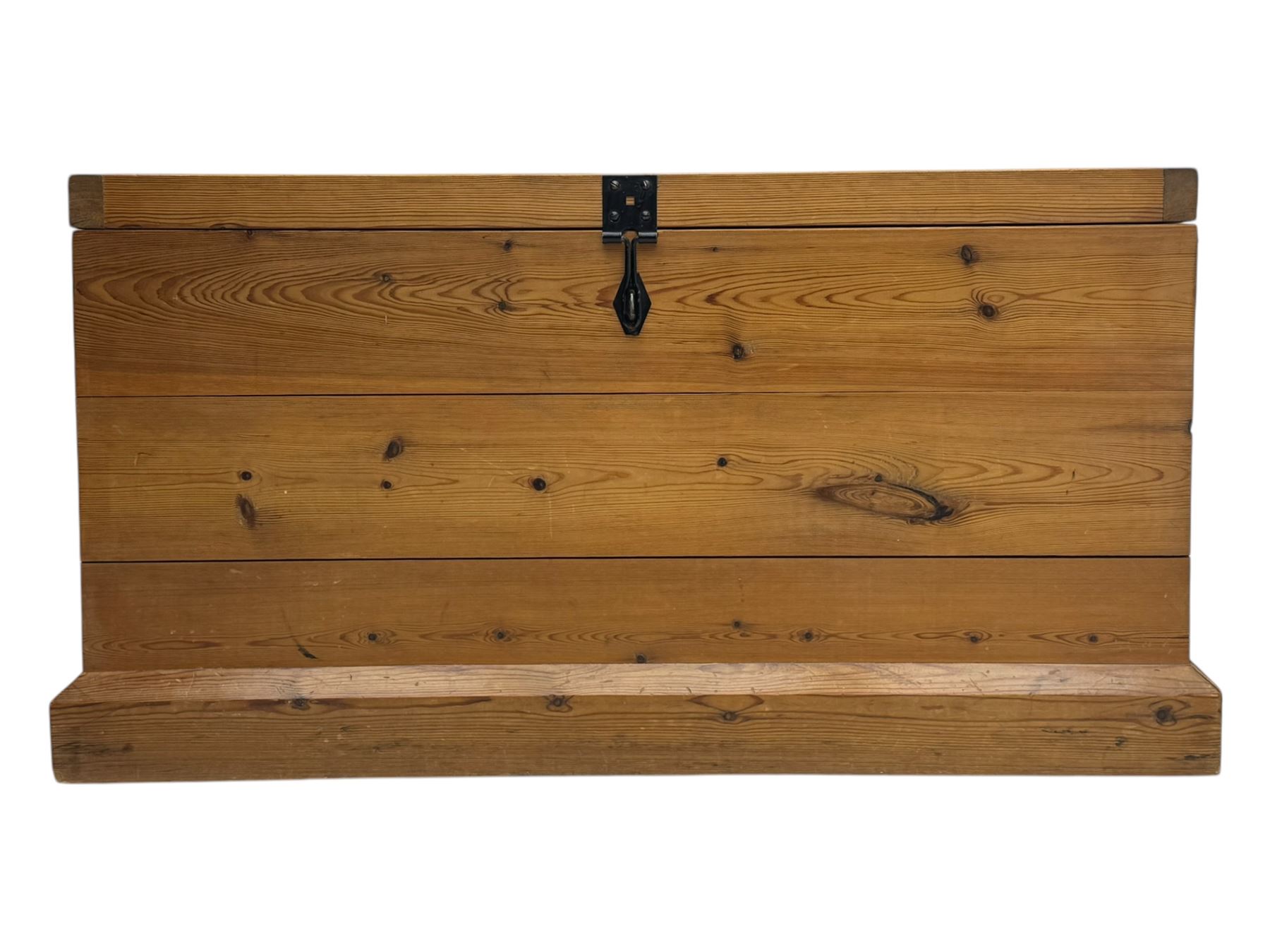 Contemporary polished pine blanket chest, the hinged planked lid with iron strap hinges and clasp fitting, plain boarded sides, fitted with blackened metal drop handles, on a moulded plinth base