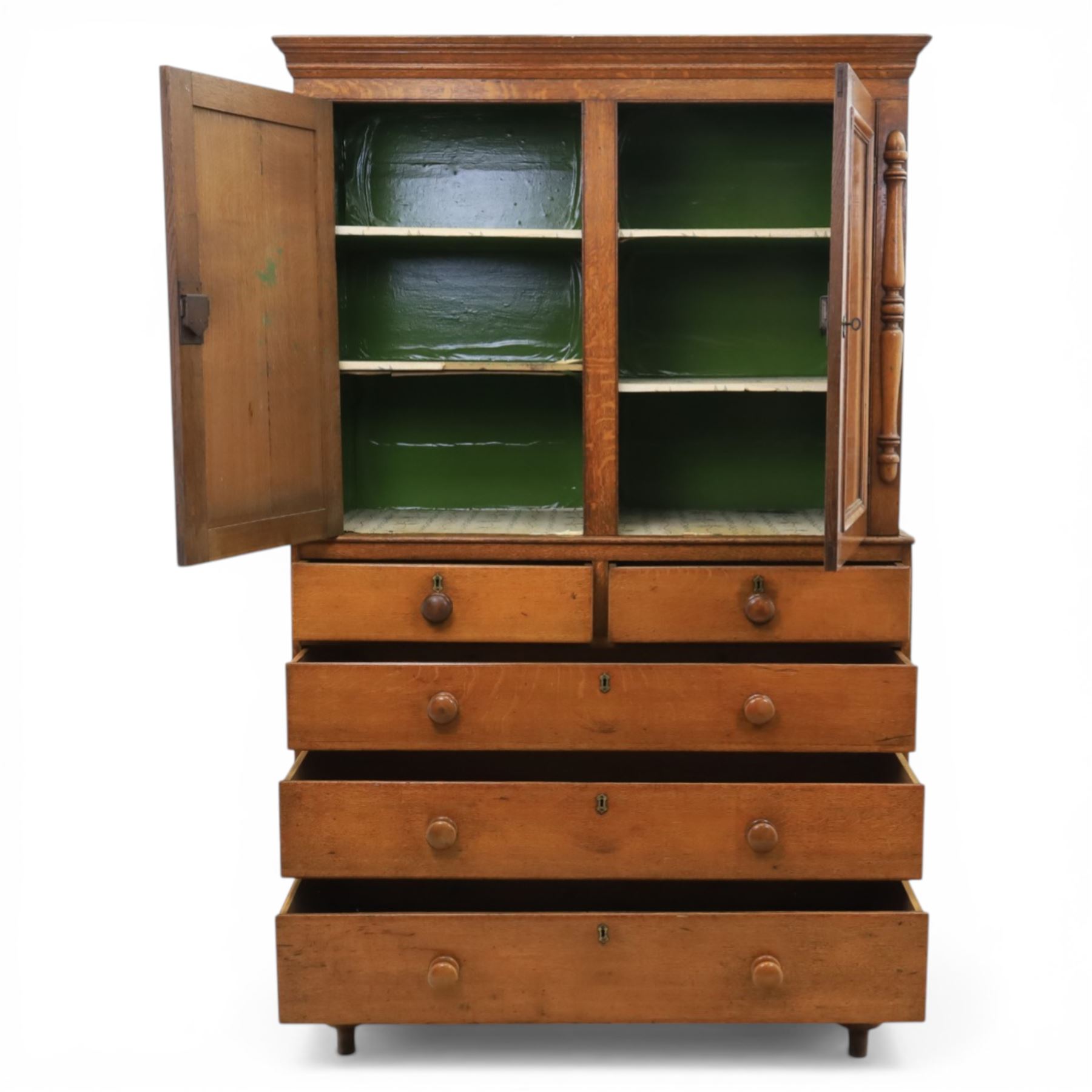 Late 19th century country oak cupboard on chest, cornice top above twin recessed panel doors with central escutcheons, flanked by turned pilasters, the lower chest with two short and three long drawers fitted with turned knob handles, on turned feet