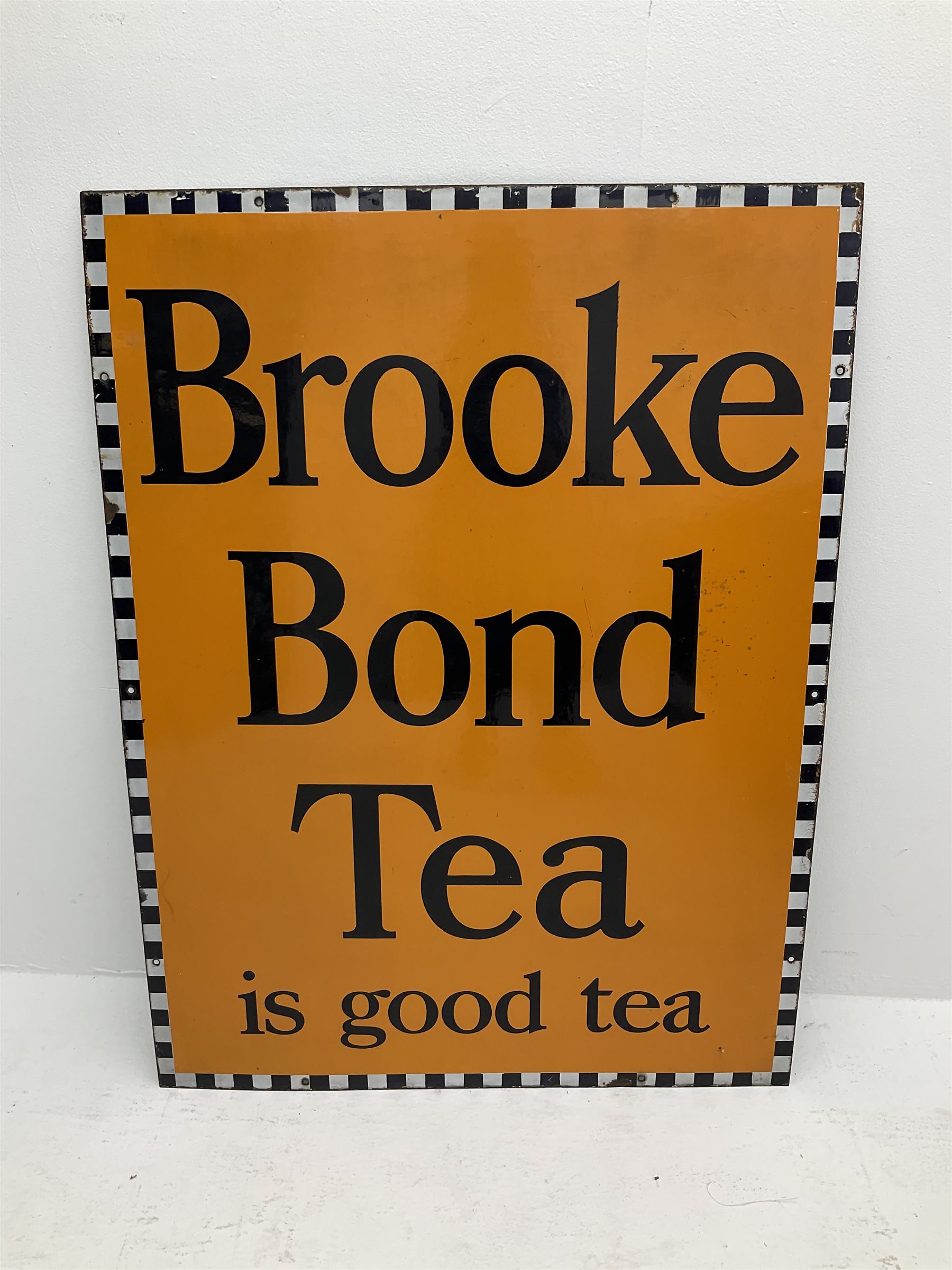 A large enamel advertising sign for Brooke Bond tea, detailed 'Brooke Bond Tea is good tea' in black lettering upon an orange ground with black and white chequered border, H101.5cm, W76cm. 