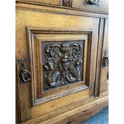 Late 19th century Arts & Crafts period oak mirror back sideboard, shaped bevelled mirror back carved with foliate scrolls and flower heads, down swept supports with elongated club-shaped uprights, moulded rectangular top over two drawers and three cupboards, the drawer fronts with copper handles decorated with sailing ships, panelled doors carved with mythical beasts, flowerheads and foliage, on moulded block feet