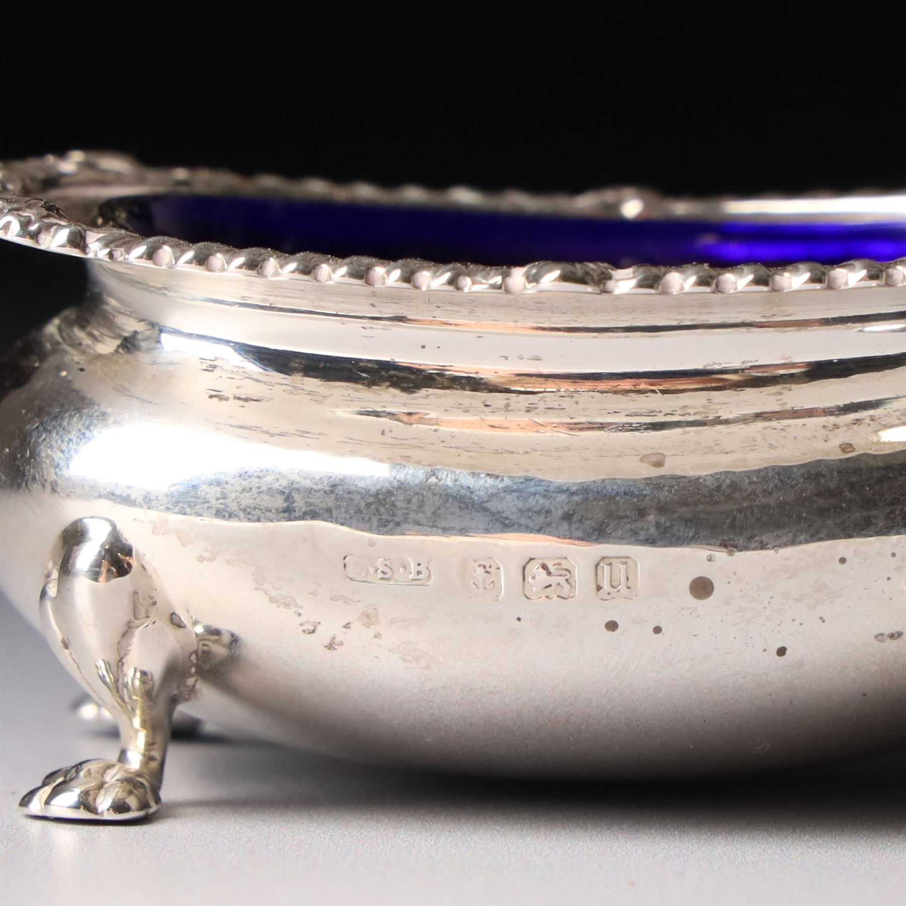 Silver salt and mustard pot with gadrooned edge on paw feet and with blue glass liners Birmingham 1919 and a similar pepperette