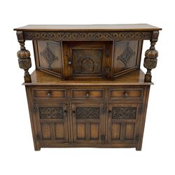 20th century carved oak court cupboard, s-scroll carved frieze over panelled cupboard door carved with arch, lobe and scroll carved cup and cover supports, fitted with three drawers and three cupboards below