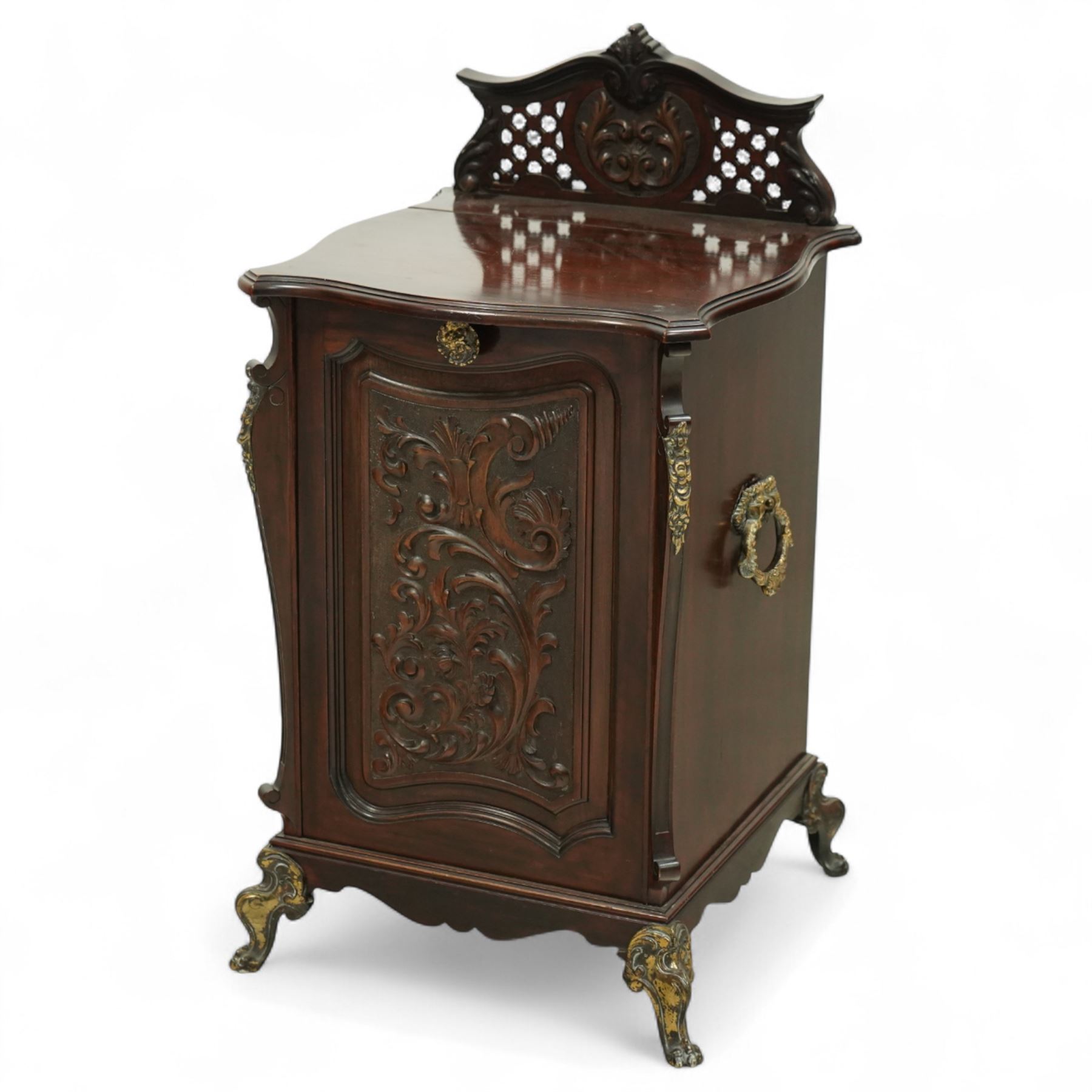 Late Victorian mahogany coal purdonium, the serpentine front door carved with scrolling foliage, surmounted by a pierced and foliate crest, brass carrying handles to sides, gilt metal mounts and cabriole legs