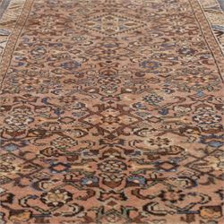 North West Persian Malayer hand-knotted runner, camel pink field decorated with an all-over lattice of Herati design, composed of rosettes and enclosed by angular leaves and stylized fish motifs, principal border of ivory ground decorated with stylized angular vine scroll and geometric palmettes, flanked by narrow guard stripes, with cotton fringe ends 