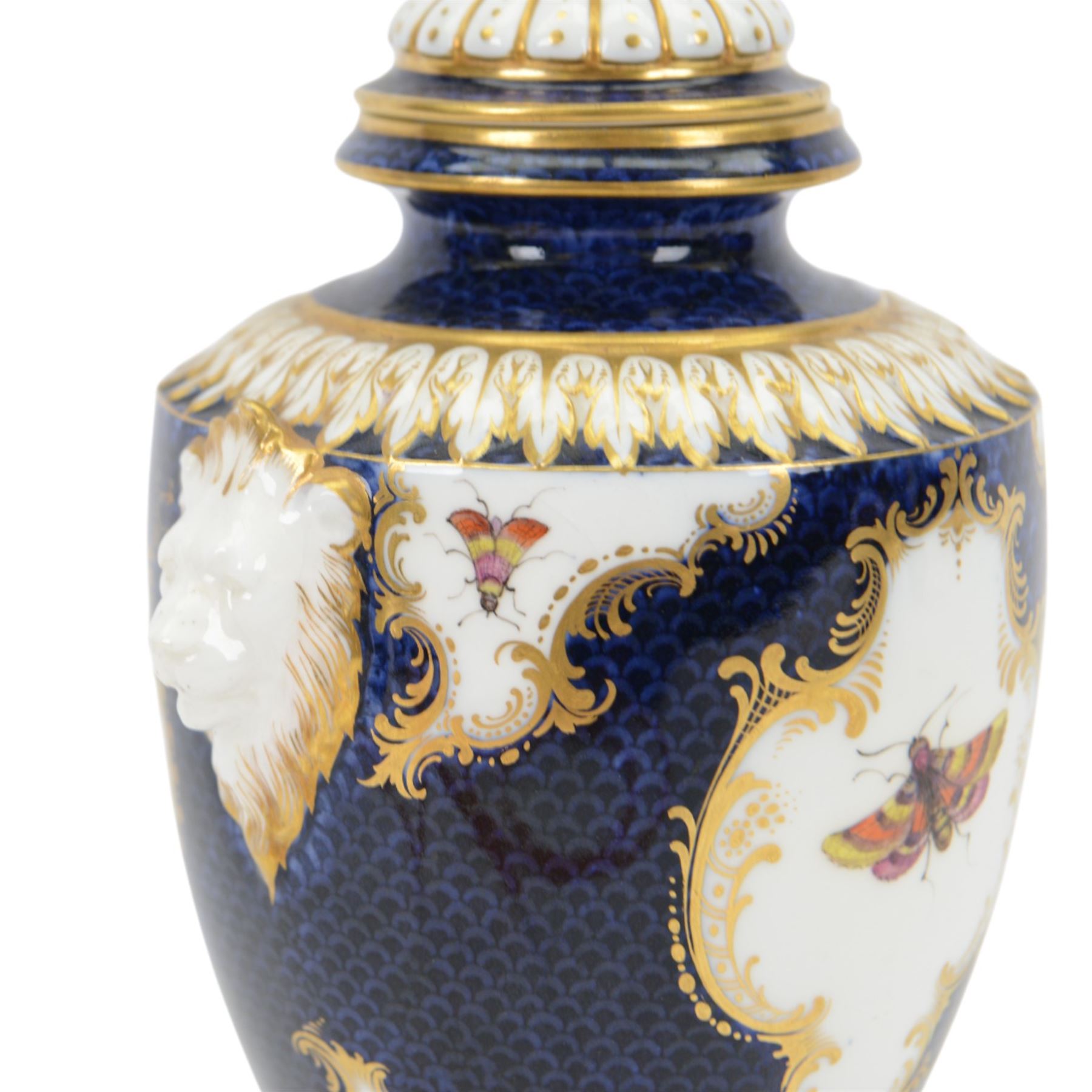Late 19th century Royal Worcester porcelain vase and cover, circa 1897, of baluster form with twin lion masks to shoulders, painted with a reserve of exotic birds within a landscape, against a blue scale ground with gilt highlights, and further detailed with smaller reserves containing butterflies, the shoulder, base of body and foot with moulded acanthus bands, upon a circular spreading foot, with green printed marks beneath including shape number 2305 and Rd no 419210, H27.5cm