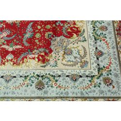 Persian silk inlaid crimson ground Kashan rug, the central shaped field with a floral pole medallion surrounded by trailing floral motifs and festoons of flowerheads, the wide cyan guard line with repeating palmettes and scrolling floral vines