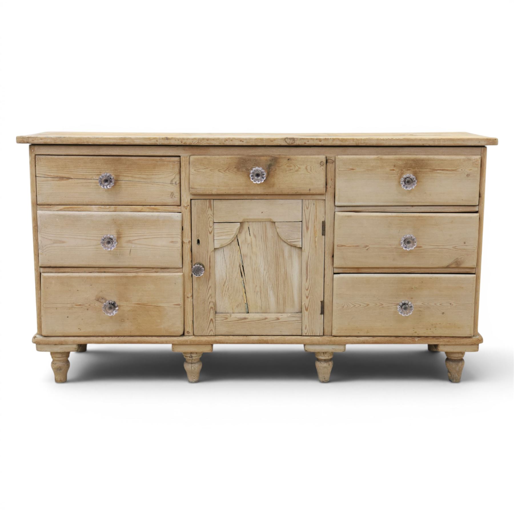 Victorian waxed pine farmhouse dresser, featuring seven drawers with central cupboard, moulded glass handles, raised on turned feet