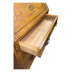 Early 20th century Arts and Crafts oak bureau bookcase, twin leaded and glazed stained glass doors enclosing two shelves, over bureau section with fall-front inlaid with sunburst motif, fitted interior of pigeonholes and shelves, on bracket feet