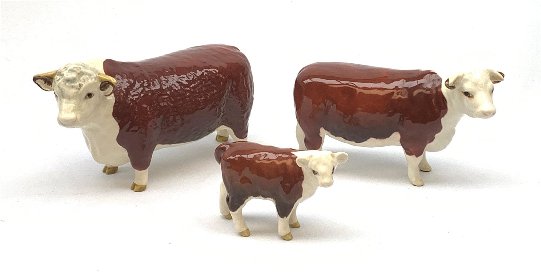 A Beswick Hereford Bull, Hereford Cow, and Hereford Calf, each with printed mark beneath, Bull and Cow marked CH of Champions. 
