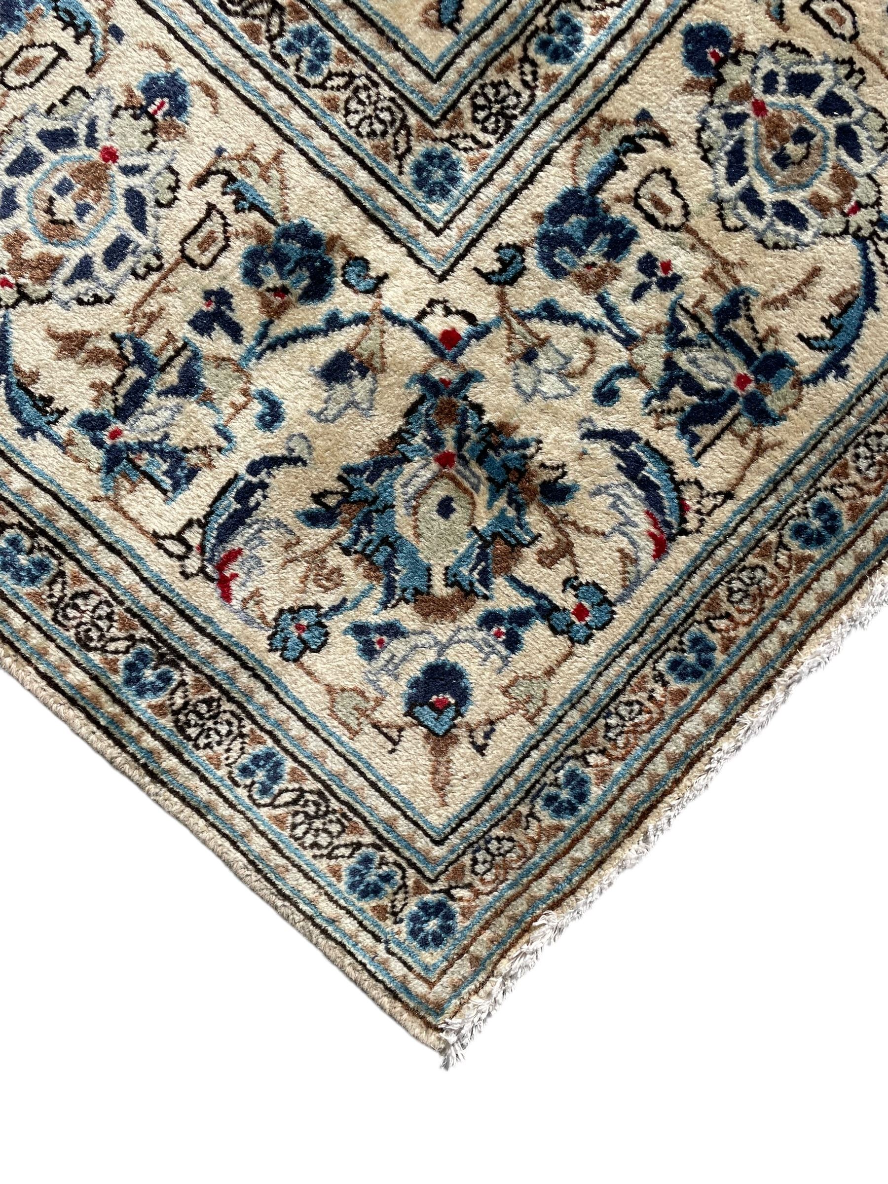 Persian Kashan ivory ground rug, the field decorated with trailing branches with leaves and palmettes, similar scrolling border, within floral pattern guard stripes 