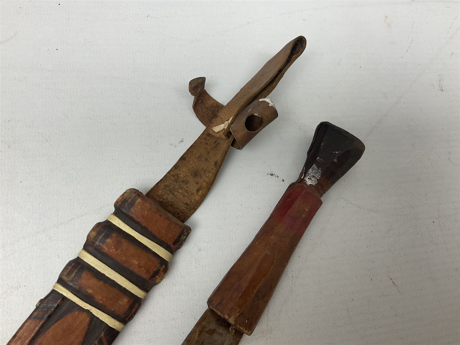 Indian kukri with 29cm curving steel blade and nickel mounted horn grip; in leather covered scabbard with one skinning knife L42cm overall; Hitler Youth knife with scabbard in relic condition; and three African graduated knives each with crudely carved wooden grips and painted leather covered scabbards (5)