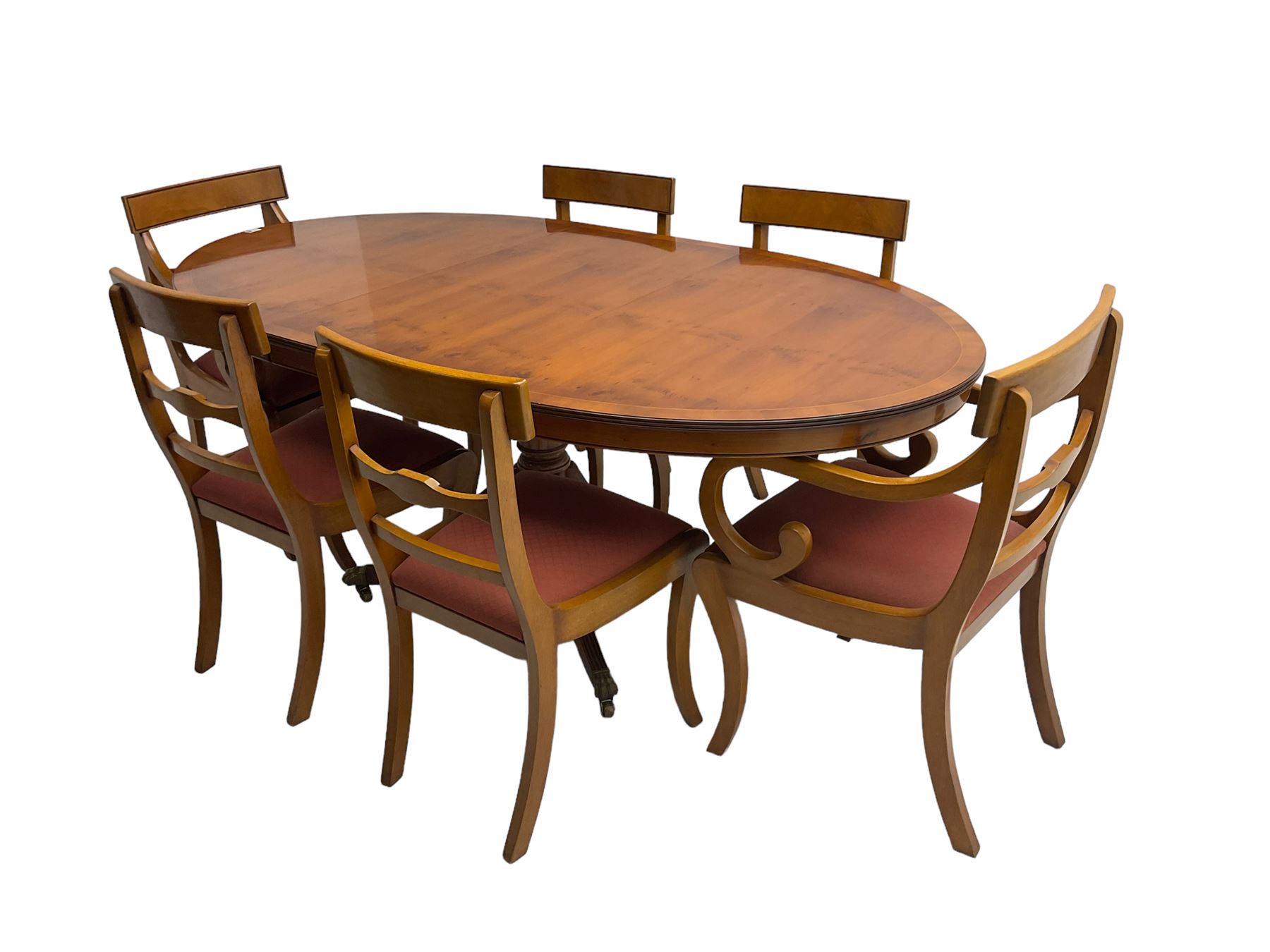 Regency design yew wood dining table, oval cross-banded top with reeded edge, raised on turned pedestal with reeded sabre supports terminating in brass hairy paw feet and castors (W138cm D100cm H75cm); and Rackstraw - set six (4+2) Regency design dining chairs with red drop-in seats (W50cm H86cm)