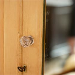 Victorian waxed pine wardrobe, carved projecting cornice with mirrored door, enclosing clothes hooks and rail, above a single drawer with glass knobs