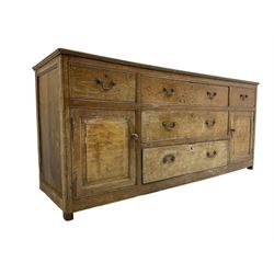 George III stripped oak dresser base or sideboard, fitted with three graduating central drawers, flanked by two drawers and panelled cupboards, on stile supports