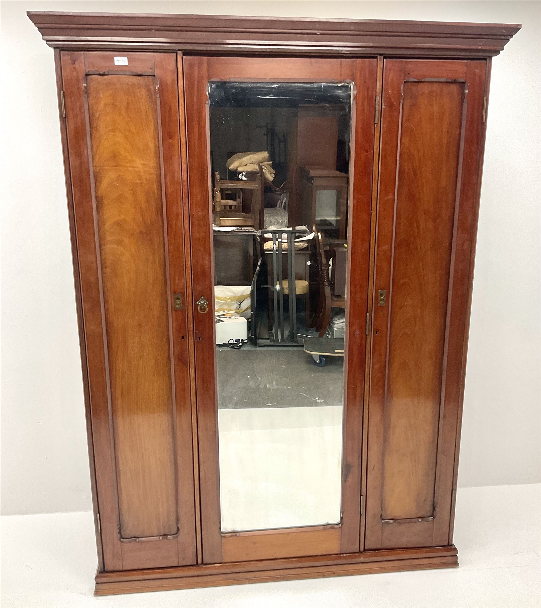 Victorian mahogany triple wardrobe, central mirrored door enclosing linen slides and two short and two long drawers flanked by two cupboards, plinth base